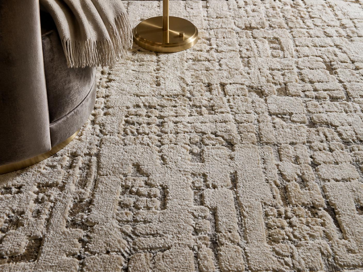 Detail of a luxurious hand-tufted designer area rug in ivory and taupe tones